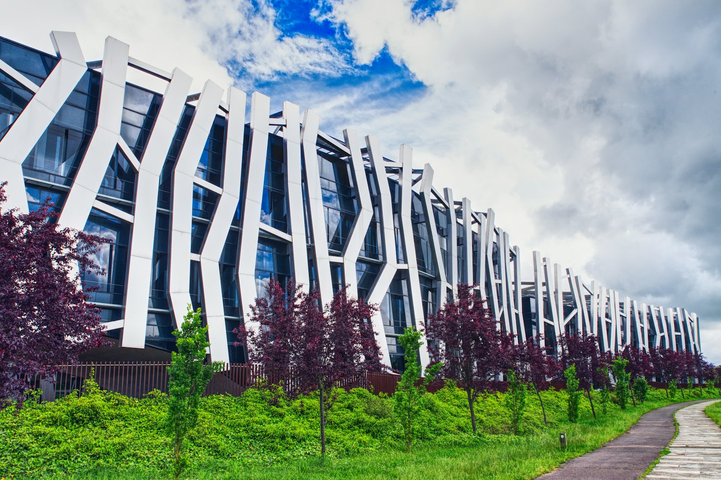 Modern angular commercial building with landscaping and pathway.